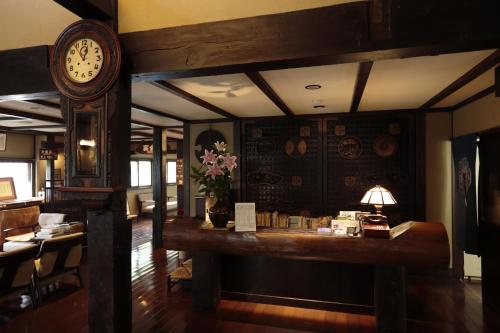a room with a clock and a table with flowers at Shirakabe in Izu