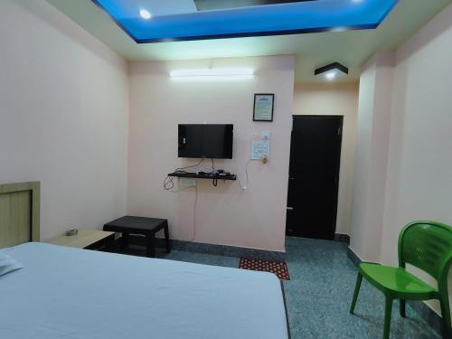 a room with a bed and a tv on the wall at GULAB LODGE in Siliguri