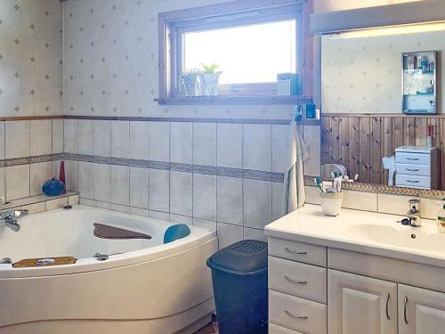 ein Badezimmer mit einer Badewanne und einem Waschbecken in der Unterkunft Holiday home Vikholmen 