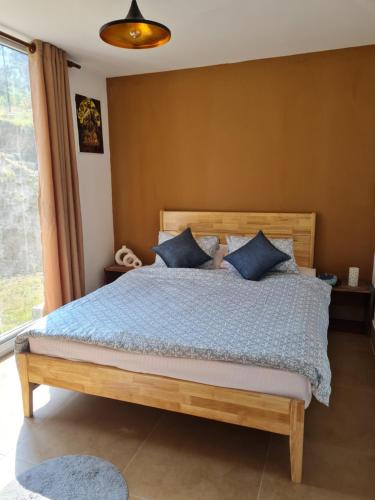 La Grange Farmhouse Dhulikhel في دهوليكهيل: غرفة نوم مع سرير خشبي مع وسائد زرقاء