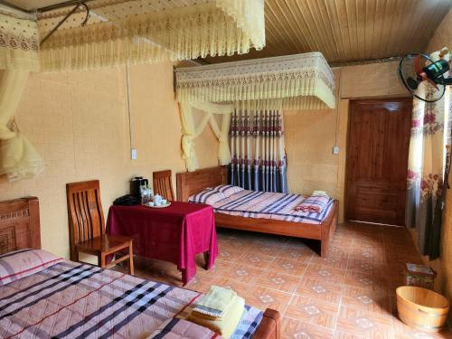 - une chambre avec 2 lits, une table et des chaises dans l'établissement Vạn Duy Homestay, à Quản Bạ