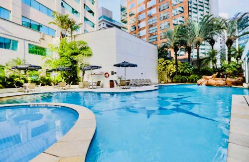 a large swimming pool with chairs and umbrellas at Vila Olimpia Suíte Inside Radisson Hotel in São Paulo