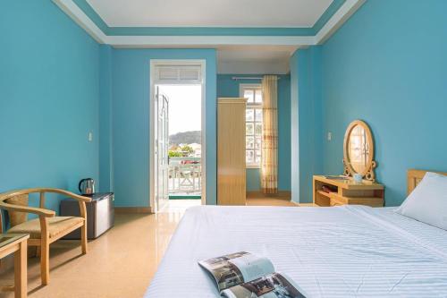 um quarto com paredes azuis e uma cama e uma cadeira em Kim Long Hotel Đà Lạt em Da Lat