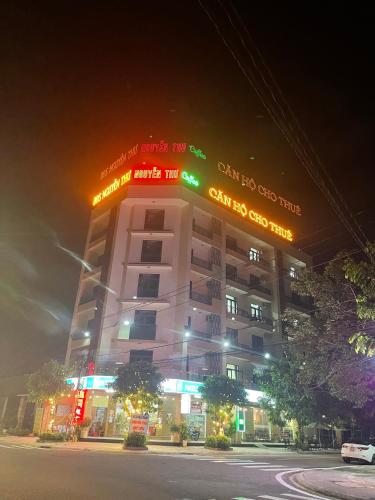 un edificio alto con letreros de neón por la noche en Nguyễn Thư Homestay, en Chánh Long