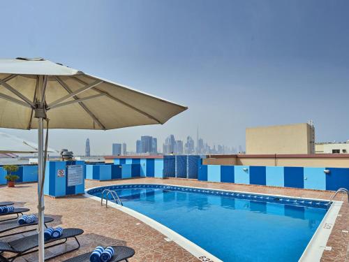 a pool on top of a building with chairs and an umbrella at Arabian Dreams Hotel Apartments in Dubai