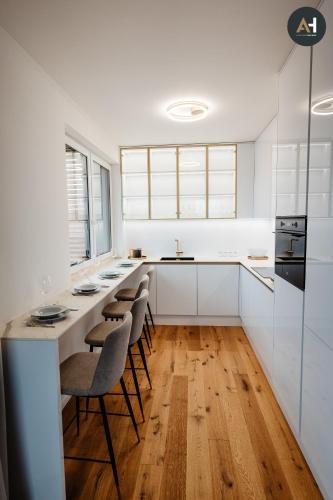 a kitchen with white cabinets and a counter with stools at Albelli Luxury Skyview in Košice