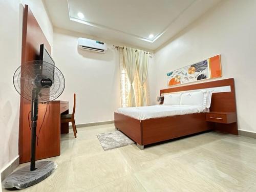 1 dormitorio con 1 cama, escritorio y ventilador en Asher’s Villa en Garki