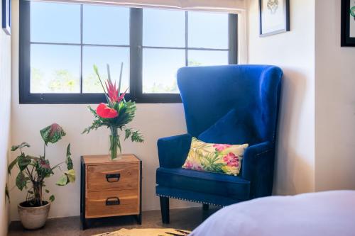 a blue chair in a bedroom with a vase of flowers at THE SWAN BINGIN - 360 Ocean & Uluwatu Hills View in Bingin Beach in Uluwatu