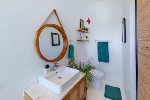 a bathroom with a sink and a mirror and a toilet at THE SWAN BINGIN - 360 Ocean & Uluwatu Hills View in Bingin Beach in Uluwatu