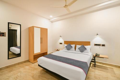 海得拉巴的住宿－Townhouse De Alphabet Karmanghat，卧室配有一张白色大床和镜子