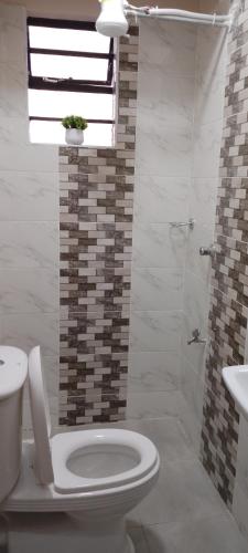 La salle de bains blanche est pourvue de toilettes et d'un lavabo. dans l'établissement Glory homes, à Nairobi