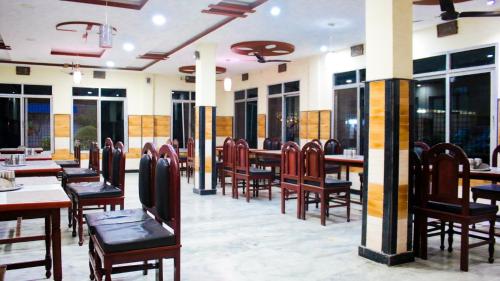 un restaurante con mesas y sillas de madera y ventanas en Hotel Pahuna Ghar, en Nepālganj