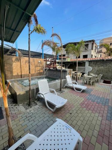 a patio with white chairs and a fountain with trees at Casa Halley #6 con vista al mar in Playas
