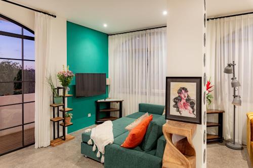 a living room with a green couch and a tv at THE SWAN BINGIN - 360 Ocean & Uluwatu Hills View in Bingin Beach in Uluwatu