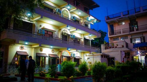 two people standing in front of a building at night at Hotel Pahuna Ghar in Nepālganj