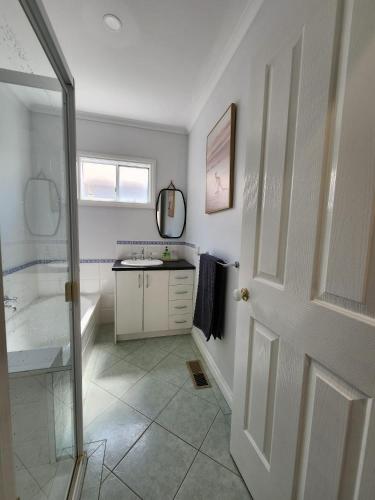 a bathroom with a sink and a shower and a door at Rye Getaway on Loatta in Rye