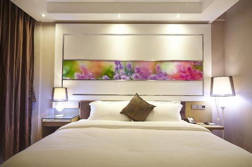 Lavande Hotel Sanya Sanya Bay Jixiang Street في سانيا: غرفة نوم بسرير كبير ولوحة على الحائط