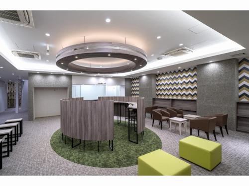 a lobby with a bar and some chairs and tables at Capsule Hotel J Garden Shin-Osaka in Osaka