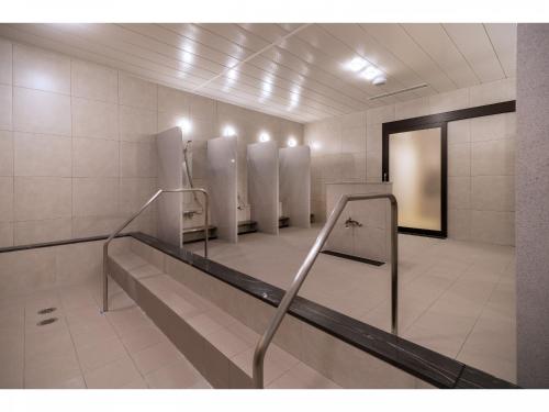 a bathroom with a row of urinals at Capsule Hotel J Garden Shin-Osaka in Osaka