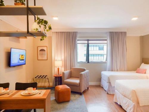 um quarto de hotel com uma cama, uma cadeira e uma secretária em EASY STAR - Flat Aconchegante ao lado da Av Paulista - AK01H em São Paulo