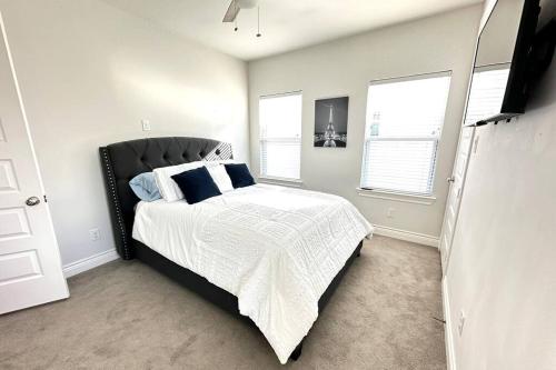 a bedroom with a bed with a black headboard and two windows at Townhouse in Houston in Houston