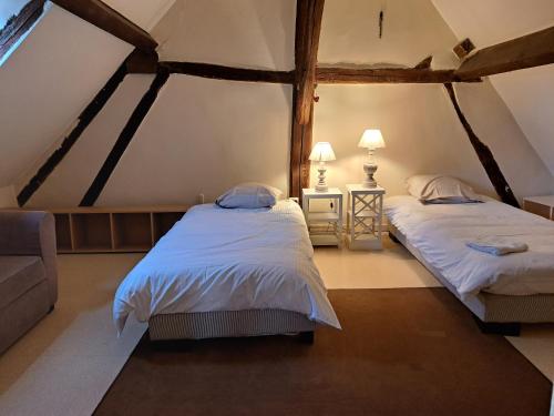 um quarto com 2 camas e um sofá em Gîte dans le parc d'une maison ancienne près des bords de Loire em Ouzouer-sur-Trézée