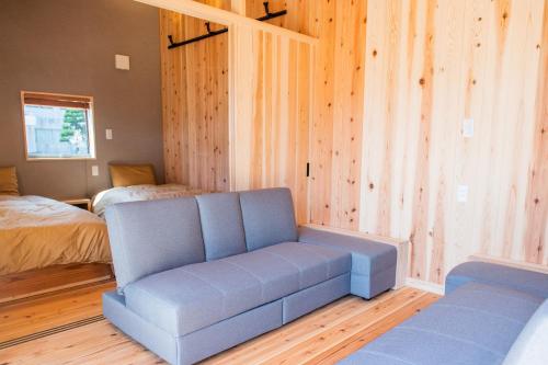 een woonkamer met een bank en een bed bij 木を楽しむ一棟貸しの宿「ウッドヴィラ 心楽 -SHIGURA-」 in Tamba
