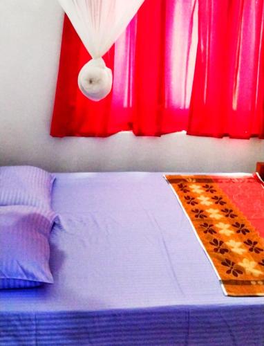 1 dormitorio con 1 cama con cortinas rojas en Dambulla Eco Homestay., en Dambulla