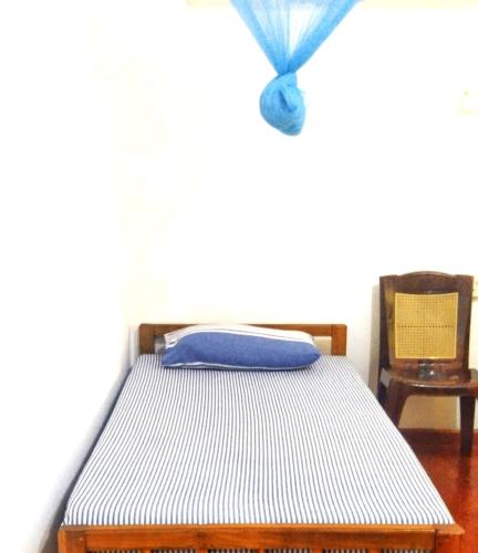 Una cama en un dormitorio con una cortina azul encima. en Dambulla Eco Homestay., en Dambulla