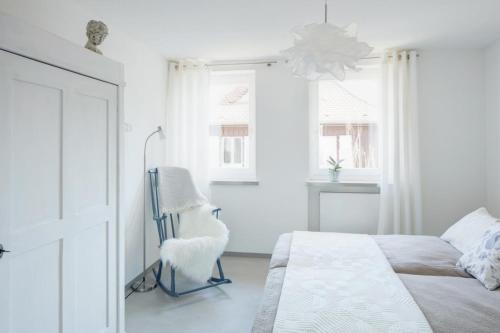 a white bedroom with a bed and a chair at Ferienwohnung Am Stadtpark in Schwäbisch Hall