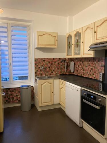 una cocina con armarios blancos y electrodomésticos negros en La Résidence 1 en Le Mont-Dore