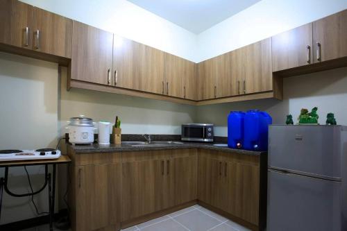 Una cocina con gabinetes de madera y refrigerador. en Asteria Residences Annabel CozyPlace highspeed wifi, en Manila