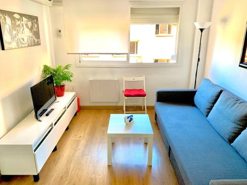 a living room with a blue couch and a table at Ana's Apartment parking gratuito in Málaga