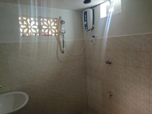 ein Bad mit einer Dusche und einem Waschbecken in der Unterkunft THE DEN in Weligama