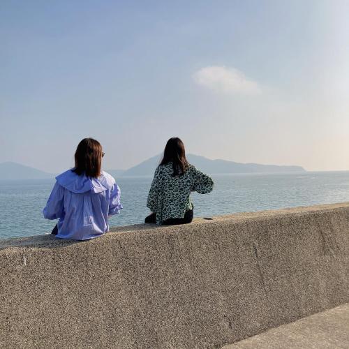 two women sitting on a wall looking at the ocean at Private Chill Base たまて 三豊市荘内半島の古民家宿 一棟貸しも可 in Mitoyo
