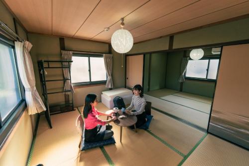two women sitting at a table in a room at Private Chill Base たまて 