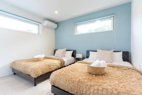 two beds in a room with blue walls and windows at グランディオーソ沖縄プールヴィラ恩納9 in Onna