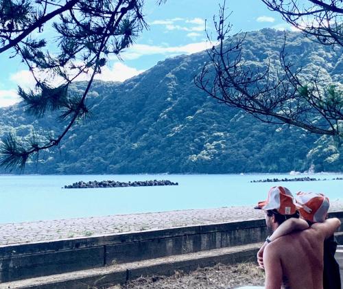 a man sitting on a bench looking at a lake at Kanzaki Beach House in Kanzaki