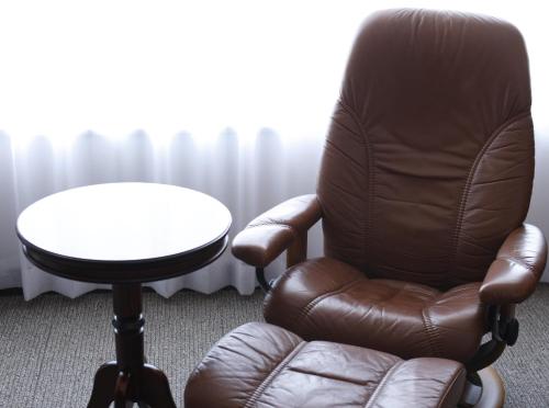a brown chair with a table and a white table at Bellevue Garden Hotel Kansai International Airport in Izumi-Sano