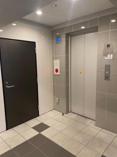 a hallway with two elevators and a black door at SkyHotel Ryogoku 駅徒歩4分 in Tokyo