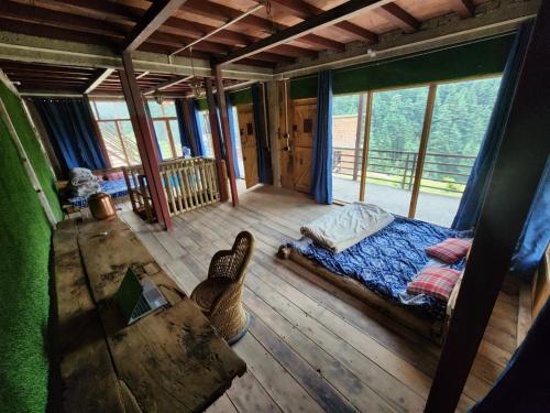 a room with a bed and a table and windows at Shoonya Home Stay - Devalsari Deodar Forest Range - 60min from Mussoorie in Mussoorie