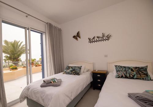 a bedroom with two beds and a window with a balcony at 105 Kings Palace - Fabulous 2 Bed, 2 bath, Large Patio with Garden - Sea Views in Paphos City