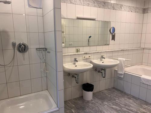 ein Badezimmer mit zwei Waschbecken, einer Badewanne und einem Spiegel in der Unterkunft Gasthof Kreuz in Bad Waldsee