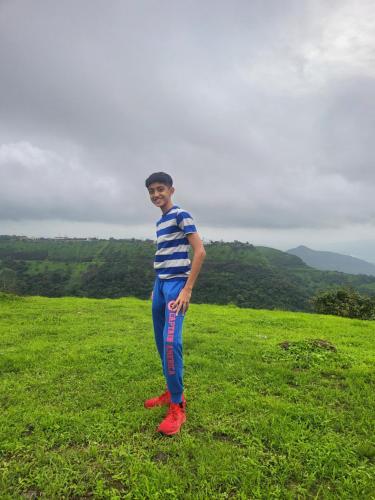 a young man standing in a field of grass at Dukes Den Resort in Lonavala
