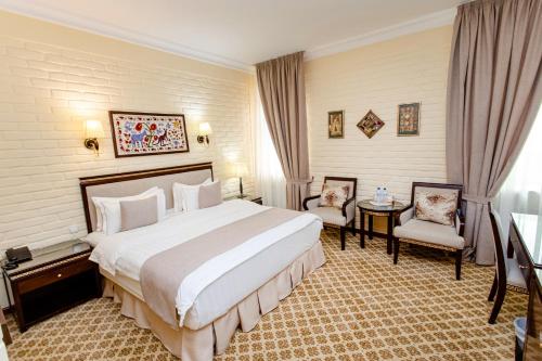 a hotel room with a large bed and two chairs at Hotel Grand Samarkand Superior - A in Samarkand