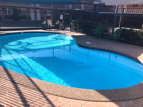 a swimming pool with blue water in a yard at Narellan Motor Inn in Narellan