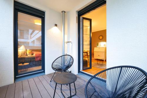 zwei Stühle und ein Tisch auf einer Veranda in der Unterkunft Blue Chili 33 - Modernes & gemütliches Business Apartment am Airport BER in Schönefeld
