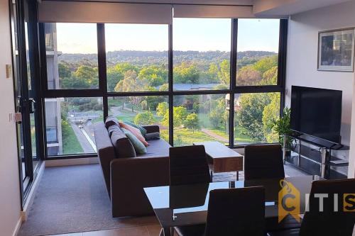 a living room with a couch and a large window at Lovely in Lyneham - 1bd 1bth Apt in Canberra