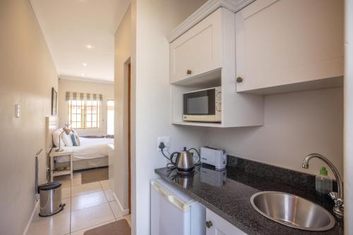 una cucina con lavandino e un letto in una camera di Lanherne Guest House Bed & Breakfast a Grahamstown