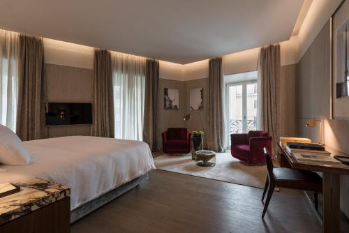 ein Hotelzimmer mit einem Bett, einem Schreibtisch und Stühlen in der Unterkunft Fendi Private Suites - Small Luxury Hotels of the World in Rom